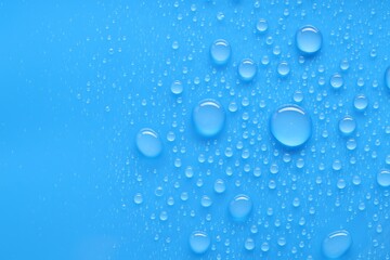 Water drops on blue background, top view