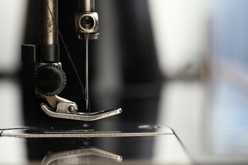 Professional sewing machine on blurred background, macro view. Space for text