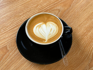 Cup of coffee latte with heart shape on old wooden background. Recently this coffee has become a trend in Indonesia. Black cup
