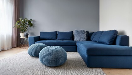 Two knitted poufs near dark blue corner sofa. Scandinavian home interior design of modern living room.