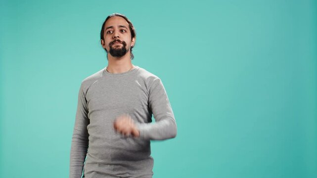 Assertive man doing stop hand gesture sign, studio backdrop. Annoyed person doing firm halt sign gesturing, wishing to end concept, isolated over blue studio background, camera B