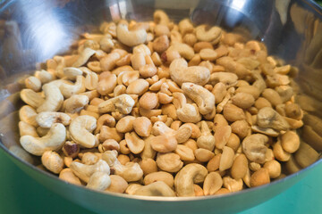 Fried peanuts and cashews arranged in an aluminum bowl