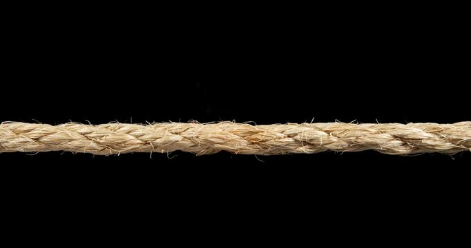 Rope stretched tight and slowly burning apart, finally snapping and breaking in two. Concept showing stress or stressful situations like divorce separation, deadlines, failure, or nervous tension.