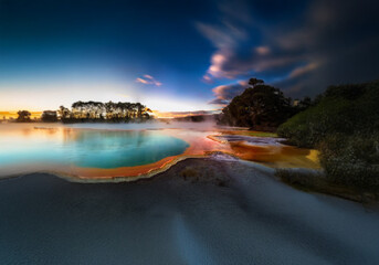 A colorful hot spring with steaming water and a colorful landscape.