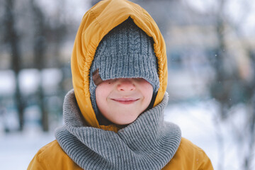 A joyful child enjoys the winter weather, bundled in warm clothing including a bright yellow jacket...
