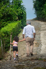 A little girl and her grandfather climbing the hill