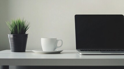 White cup of coffee and laptop on a white desk.