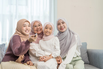 three different female generations meeting at home,sitting on couch in living room,hugging with love, smile,affection,enjoy watching TV together