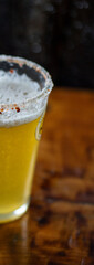 Vaso de michelada con cerveza y borde cubierto de ají merkén, sobre una mesa. Bebida refrescante con un toque picante y cítrico
