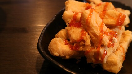 Crispy tofu with tomato sauces served on black plate, Indonesia dish