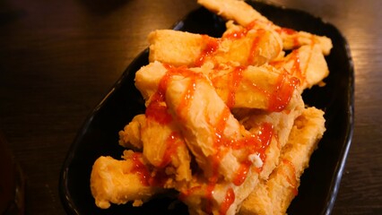 Crispy tofu with tomato sauces served on black plate, Indonesia dish