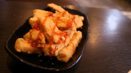 Crispy tofu with tomato sauces served on black plate, Indonesia dish