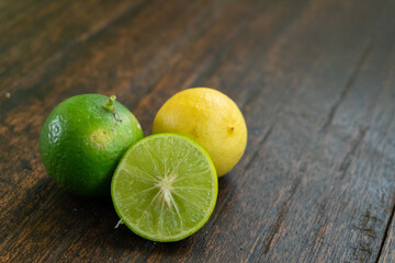 jeruk nipis or Lime green with cut in half and slices isolated on wooden background.