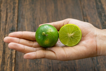 jeruk nipis or Lime green with cut in half and slices isolated on wooden background.