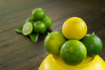 jeruk nipis or Lime green with cut in half and slices isolated on wooden background.