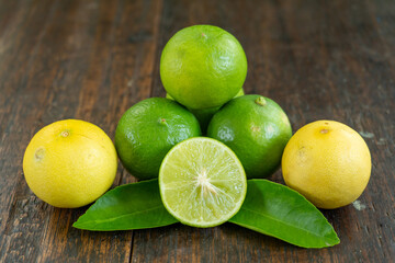 jeruk nipis or Lime green with cut in half and slices isolated on wooden background.