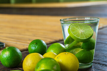 A glass of refreshing lemon water with fresh lemon slices on a wooden table.
