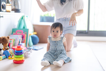 A 1 year old Taiwanese girl spending time playing happily with her parents, a man and woman in their 20s, in a room of a high rise apartment in Taichung City, Taiwan.