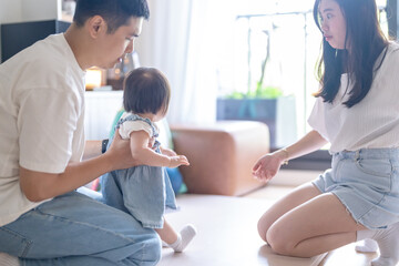 Obraz premium A 1 year old Taiwanese girl spending time playing happily with her parents, a man and woman in their 20s, in a room of a high rise apartment in Taichung City, Taiwan.