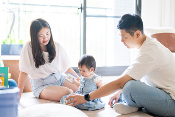 A 1 year old Taiwanese girl spending time playing happily with her parents, a man and woman in their 20s, in a room of a high rise apartment in Taichung City, Taiwan.