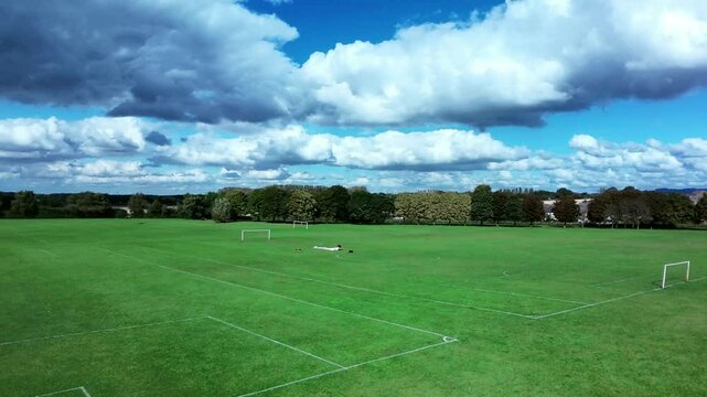 Establishing aerial view rising up over football field goal posts on local British pitch