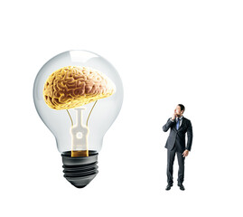 Businessman thinking near large lightbulb with brain inside
