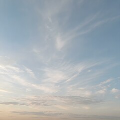 Obraz premium A tranquil dawn sky with wisps of clouds floating close to the ground, bathed in soft morning light as the day begins 