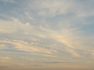 Obraz premium A tranquil dawn sky with wisps of clouds floating close to the ground, bathed in soft morning light as the day begins 