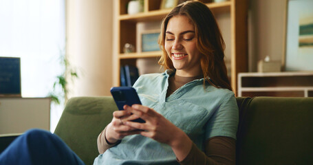 Smile, girl and relax with phone on couch for communication, social media and notification update. Happy, woman and mobile for reading message, online chat and texting of entertainment game at house