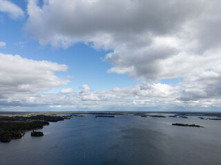 Tranquil aerial view of the 1000 Islands region, showcasing scattered islands on serene waters under a vast sky, capturing natural beauty and peacefulness.