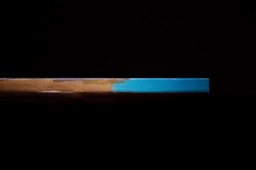 Side view of the canvas stretched on a stretcher. The concept of the modern school of art. Dark brown background. The work of art lies on a wooden table.