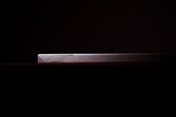 Side view of the canvas stretched on a stretcher. The concept of the modern school of art. Dark brown background. The work of art lies on a wooden table.