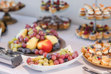 Different kinds of beautiful pastry, small colorful sweet cakes, macaron, and other dessert in the sweet buffet