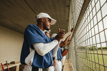 Baseball players standing in the dugout, watching the game intently with anticipation