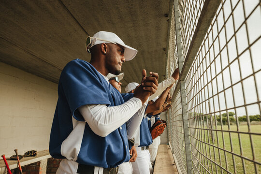 Baseball players standing in the dugout, watching the game intently with anticipation