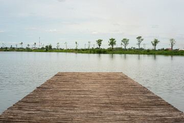 Obraz premium A wooden footbridge or boat dock over the water lake with tranquil view. Outdoor and nature view photo scene.
