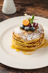 Pancakes with fruit and maple syrup on a white plate