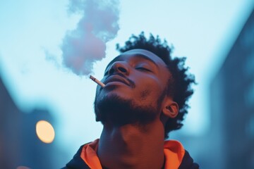 Young man smoking cigarette exhaling smoke at night