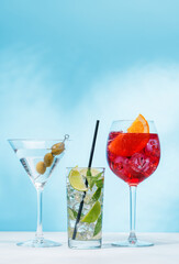 A variety of cocktails arranged on a table against a light blue background