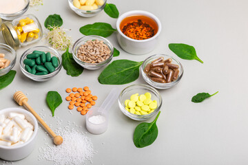 Homeopathic meds, pills, tablets, green leaves and other natural organic products in a beautiful composition on a light grey background. Homeopathy and alternative medicine.