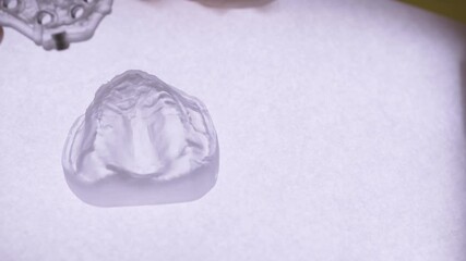 Close-up of dental implant guide model held by a dentist's hands under bright light