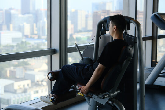 Asian young man exercise on leg curl machine in gym