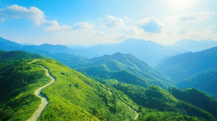 Naklejka premium A beautiful mountain view with a winding trail cutting through vibrant greenery, under a clear blue sky, perfect for outdoor content