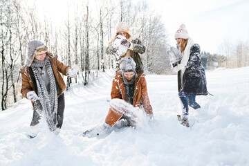 Friends in snowball fight in snowy nature, throwing snow and having fun. First snowfall of the season.