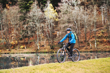 Fototapeta premium Active man on bike in the middle of beautiful nature, looking at lake. Concept of healthy lifestyle.