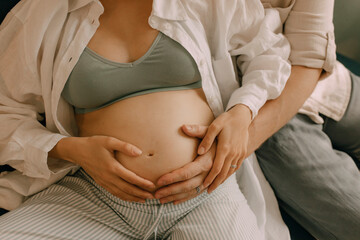 Hand of man touching pregnant wife's belly