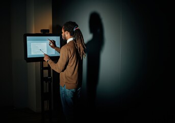 Man giving interactive presentation on digital screen in dimly lit room