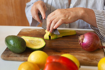 Woman cutting avocado on board
