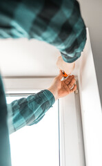 Man installs roller blinds. Handyman mesures window to fix it.