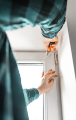 Man installs roller blinds. Handyman mesures window to fix it.